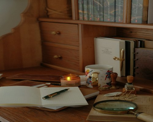 A cozy indoor setup with a notebook and a glass of water on a wooden desk