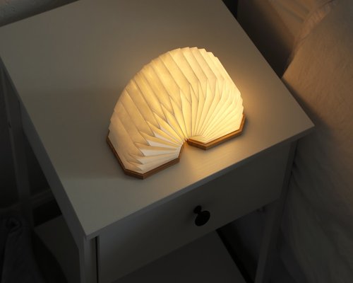 A warm desk lamp illuminating an open book on a bedside table