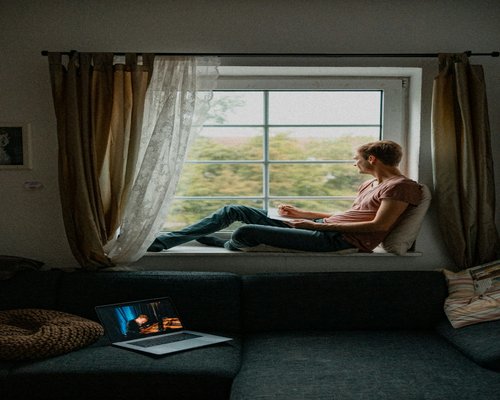 A person looking out a window taking a break from their laptop